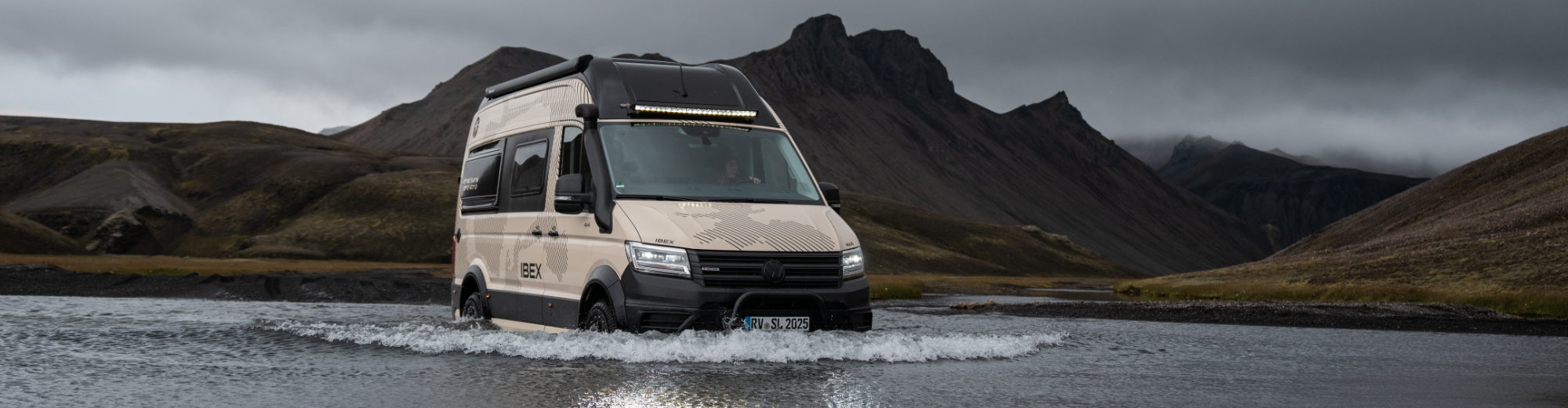 Ein weißer Camper Van steht in einer großen Pfütze.