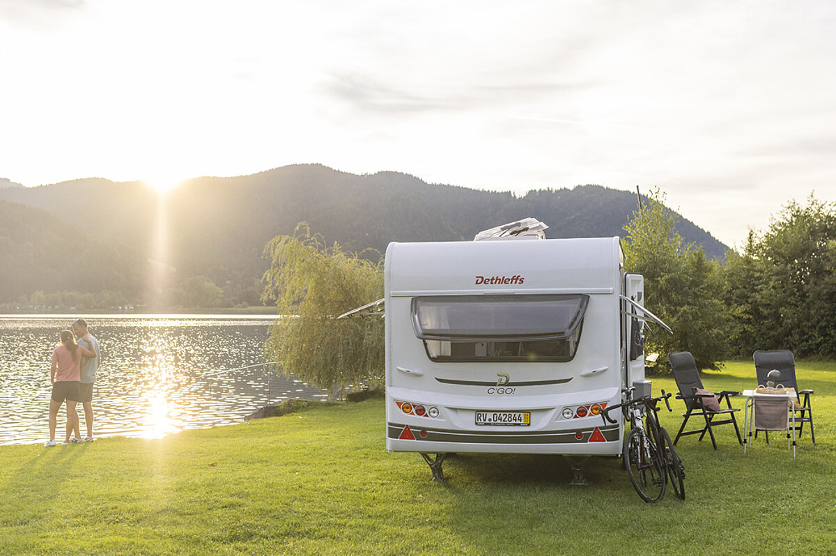 Wohnwagen steht an einem See bei Sonnenuntergang.