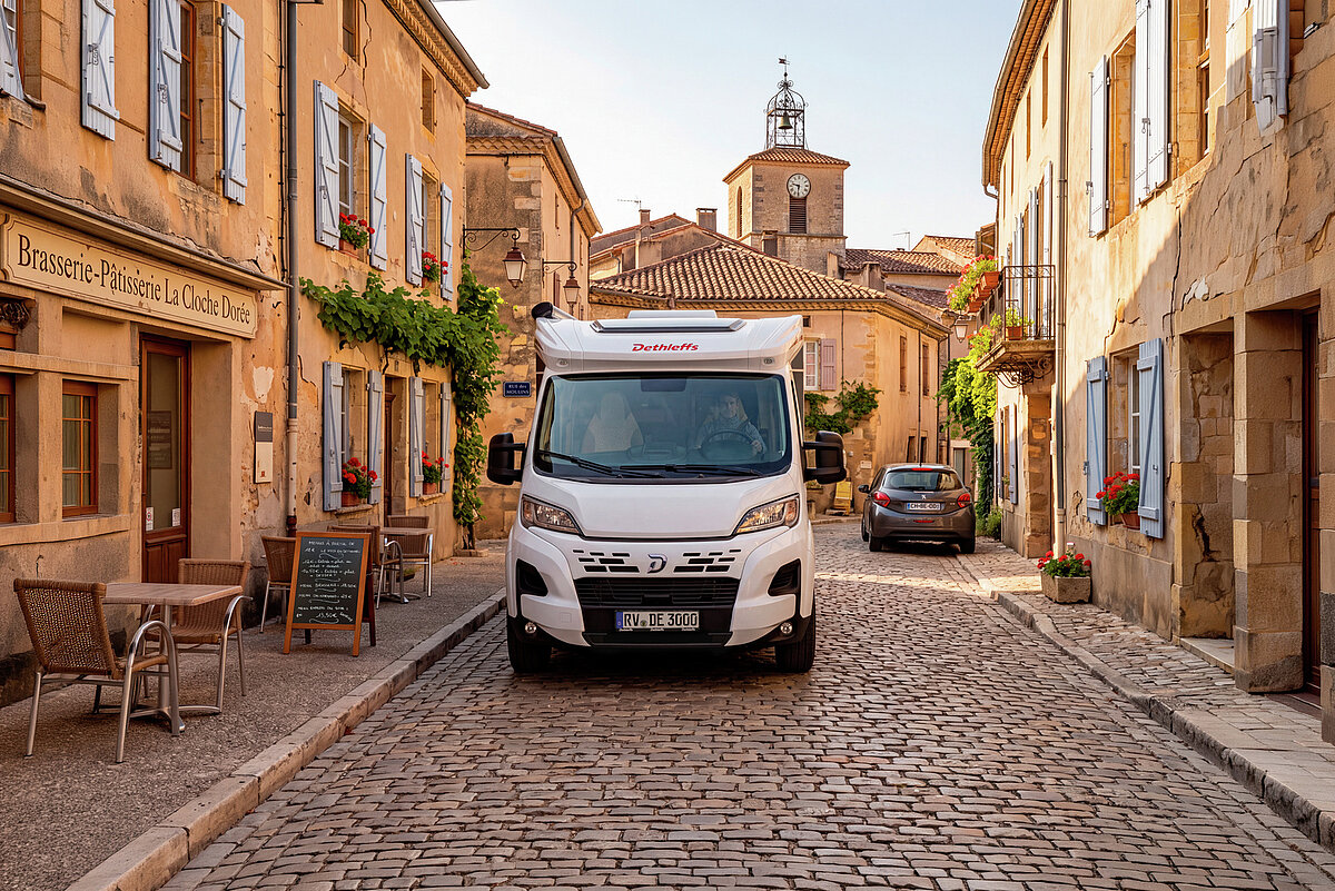 Ein Wohnmobil von vorne in einer mediterranen Altstadt.