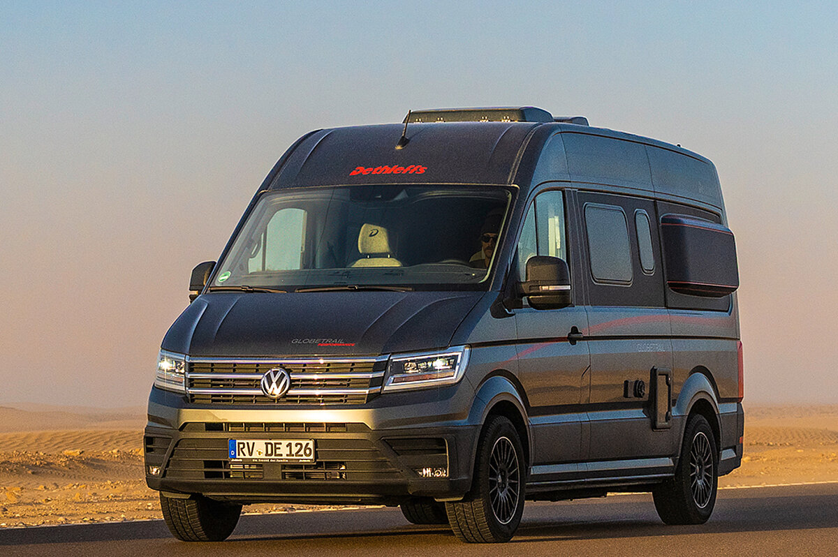 Dunkler Camper Van in einer wüstenähnlichen Landschaft.
